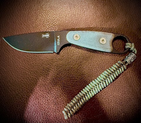 Fixed-blade knife with light blue handle and braided paracord lanyard on brown leather background