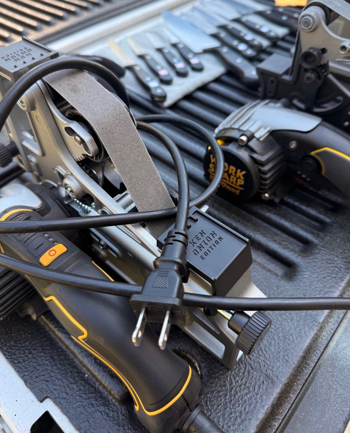 Power tools with charging cables and batteries arranged on a dark workbench, featuring yellow and black DeWalt equipment