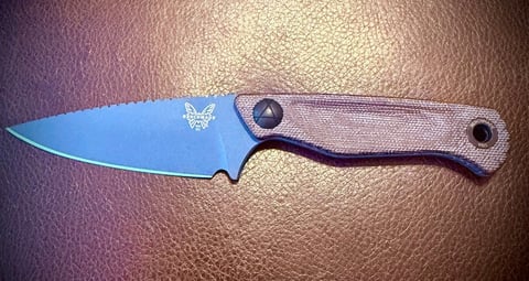 A fixed-blade knife with a blue blade and gray handle featuring a triangular logo, displayed on a leather surface