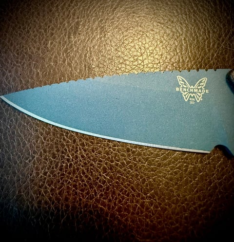 Teal knife blade with logo on textured leather surface