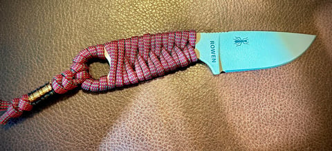 Kitchen knife with pink checkered handle on a beige fabric surface